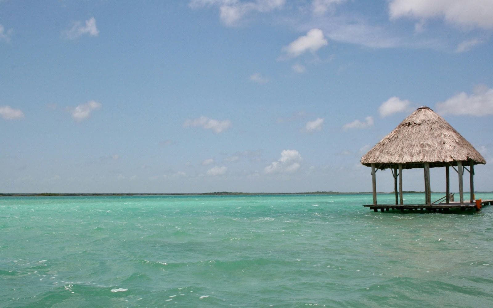 Strohgedeckter Steg in der türkisfarbenen Lagune von Bacalar, Mexiko