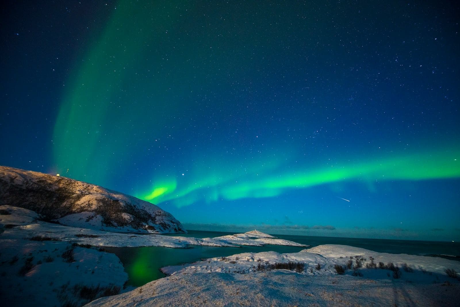 Nordlicht über einer verschneiten Küste bei Tromsø
